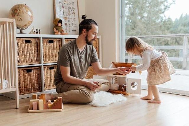 Vater spielt mit ca. 3-jähriger Tochter im Kinderzimmer. 